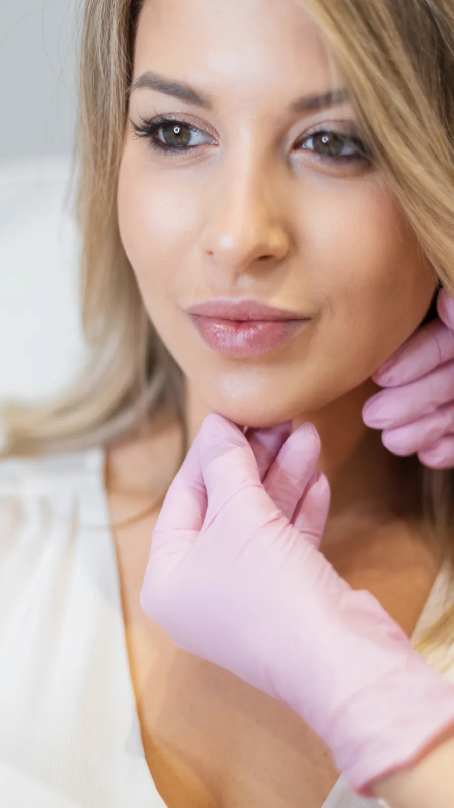 Provider in pink gloves assessing the jawline for a thread lift at Advanced Aesthetics